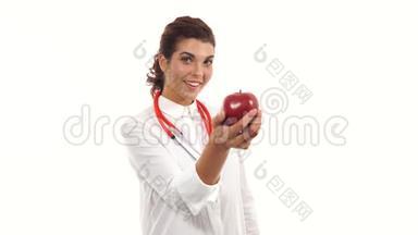 年轻的营养学家捧着红苹果，建议健康饮食。 友好的女医生露出红苹果的微笑。 肖像